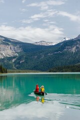 Fototapeta na wymiar Iconic wooden lodge, red kayaks, people kayaking on breathtaking Emerald Lake, Yoho National Park, Beautiful British Columbia, Canada