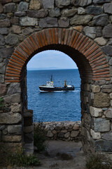 Fototapeta na wymiar Old fortress in Sozopol and a ship seen sailing through it in the sea