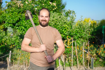 An adult male farmer with a hoe posing in the the farm. High quality photo