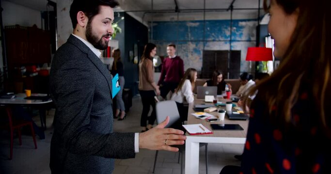 Young happy excited Asian woman taking job interview in modern multiethnic office, is greeted by male HR slow motion.