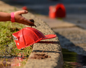 Bright red fireman's hat held out by a child's hand
