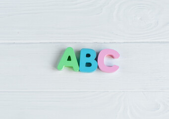 Close up Multicolored wooden letters with ABC on white wooden background. Set of toys for studying alphabet. Education, back to school concept. Top view, copy space