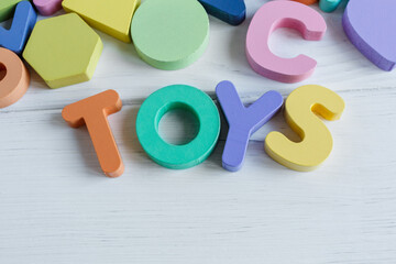 Close up Multicolored wooden letters on white wooden background. Set of toys for studying alphabet. Education, back to school concept. Top view, copy space