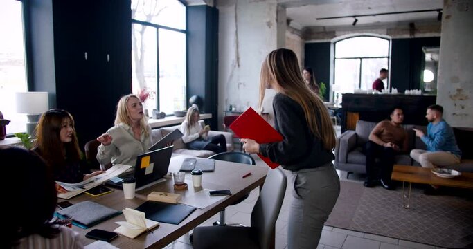 Camera follows happy successful young blonde business woman walking to colleagues at busy modern loft office slow motion
