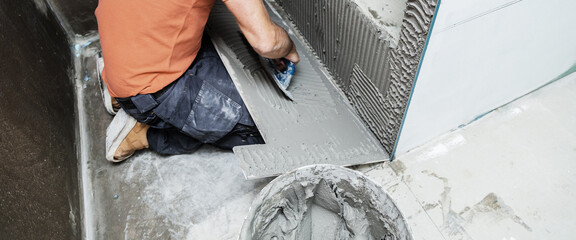 The tiler works in the bathroom of a modern house.
