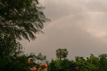 Picture of a rainy day where the rainbow has spread its beauty in the cloudy sky in a rural environment