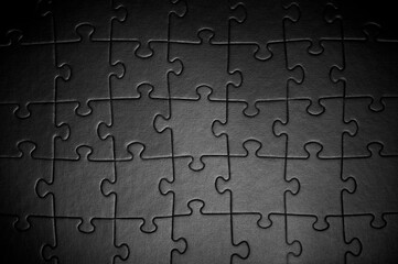 Fototapeta premium Puzzles in black. Monochrome cardboard shapes. Dark background.