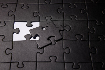 Fototapeta premium Puzzles in black. Monochrome cardboard shapes. Dark background.