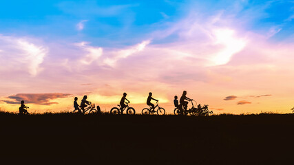 Fototapeta na wymiar Silhouette of children friends on bicycles outdoors against sunset