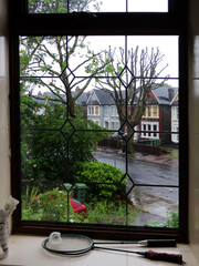 rainy day on a typical english street behind a curly glazed window and badminton rackets lie on the windowsill