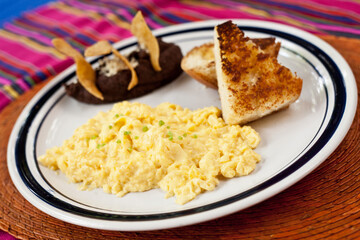 Scrambled eggs served with toast, beans, and tostadas
