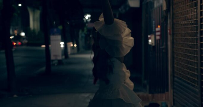 Scary Female Cosplayer Dancing in Dark Sidewalk with Cars in the Background