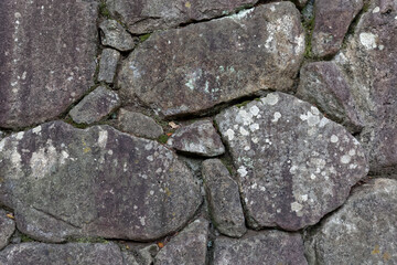 Old uneven stone wall spotted with lichen and moss