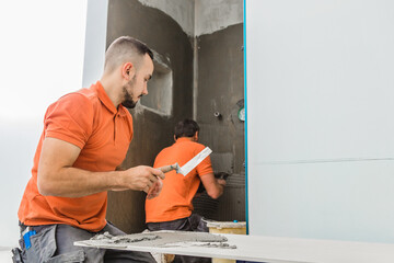 Fliesenleger Handwerker arbeitet in badezimmer eines modernen Hauses.