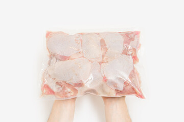Hands holding package of raw chicken on white background. Clipping path. Top view.