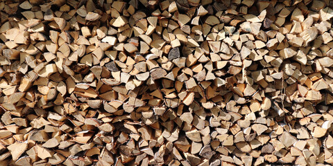 Woodpile of birch firewood lit by the sun.