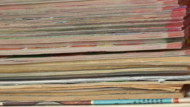 Closeup view 4k video footage of stack of many old paper magazines. 