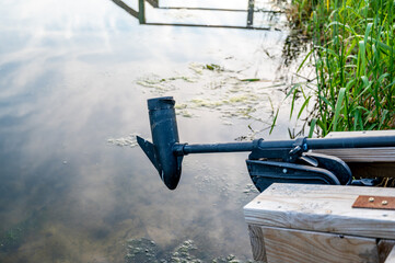 Boat trolling outboard motor extended over mossy water - obrazy, fototapety, plakaty