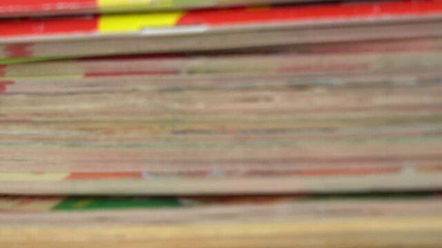 Closeup view 4k video footage of heap of many old paper magazines stacked together. 