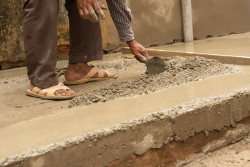Indian construction workers plastering floor using trowel and cement manually, Stock image.
