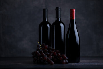 The red wine in the glass, along with a bottle of wine made from red grapes, is laid on a wooden floor and a beautiful backdrop. Ready for partying