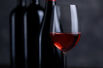 The red wine in the glass, along with a bottle of wine made from red grapes, is laid on a wooden floor and a beautiful backdrop. Ready for partying