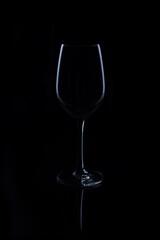 Wine glasses on light and shadow on a black background.