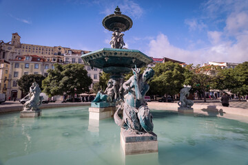 Fototapeta na wymiar Lisbon / Portugal - 11 08 2018 - Fountain in Sunny Weather with Portugal Buildings and architecture on the background