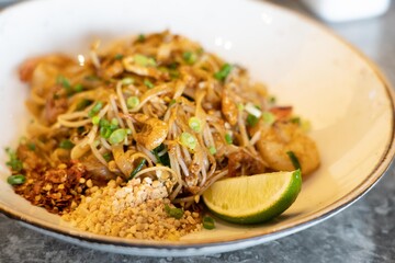 Close up image of Thailand traditional street food, Pad Thai noodles on a white plate and marble stone table.