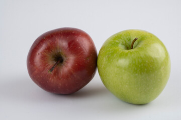 Green and red apples on a white background near each other