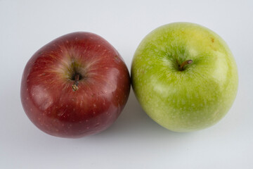 Green and red apples on a white background near each other