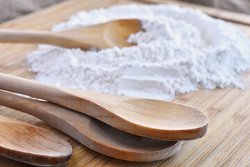 A close up image of a heap of white flour and a wooden mixing spoon. 