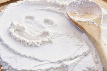 A close up image of a heap of white flour and a wooden mixing spoon. 