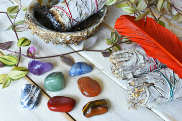 A close up image of Chakra healing crystals with white sage smudge sticks and orange sacred...