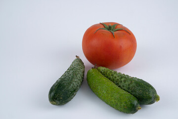 Organic cucumbers and red tomato on a white background