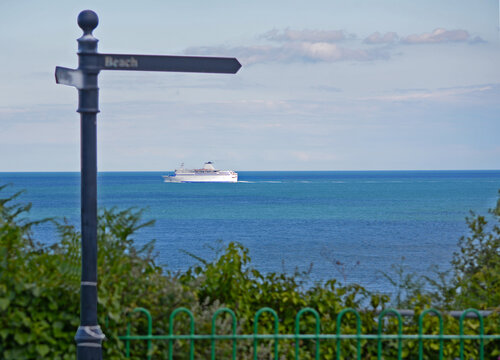 Signpost to "The Beach" with a cruise ship passing by on the horizon.