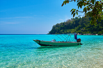 Fototapeta na wymiar Beautiful nature landscape. White sandy beach and a boat in the turquoise sea. Paradise island. Perfect getaway. Travel concept and idea.