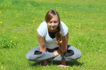 Young woman of European appearance does yoga in summer nature