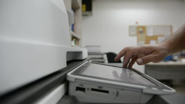 : Close up low light. Someone work on modern copy machine at office.