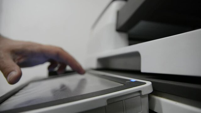 : Close up low light. Someone work on modern copy machine at office.