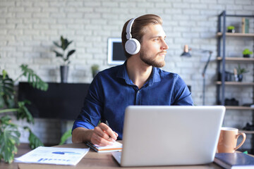 Confident man wearing headset speaking and watching business webinar training, listening to lecture.