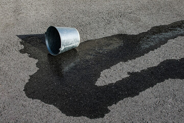 An overturned metal bucket and spilled water. Concept: failure and emptiness. © VITALII