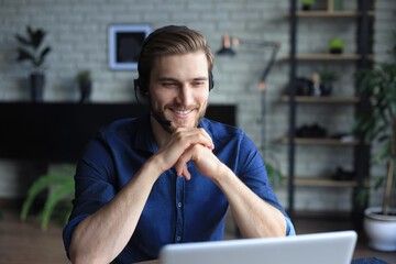 Confident man wearing headset speaking and watching business webinar training, listening to lecture.