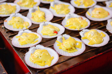 BBQ grilled scallops on fire, grilled scallops with butter and cheese, Thai sea food, grilled scallops selling at local market thailand, grilled scallops shell with butter and garlic