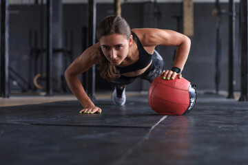 Fit and muscular woman exercising with medicine ball at gym.