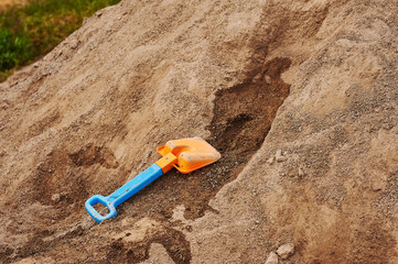 mountain of sand with a child's shovel. playing in the sand. brown mountain with children's toys