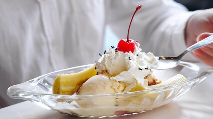 Close-up of ice cream with whipped cream, banana and cherry.