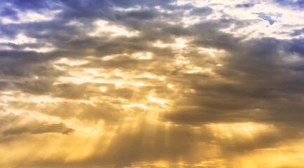 Obraz premium evening cloudy sky with mild golden light , shinig through the colored orange clouds , nature landscape background