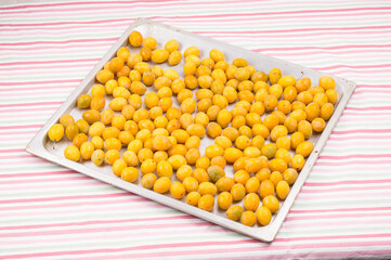 beautiful yellow home plums on aluminum tray on table with on  colorful striped tablecloth. Organic  yellow plums