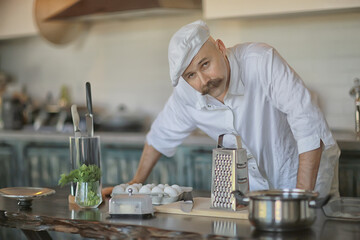 Fototapeta na wymiar french chef in the kitchen preparing food, cooking, haute cuisine, man with mustache